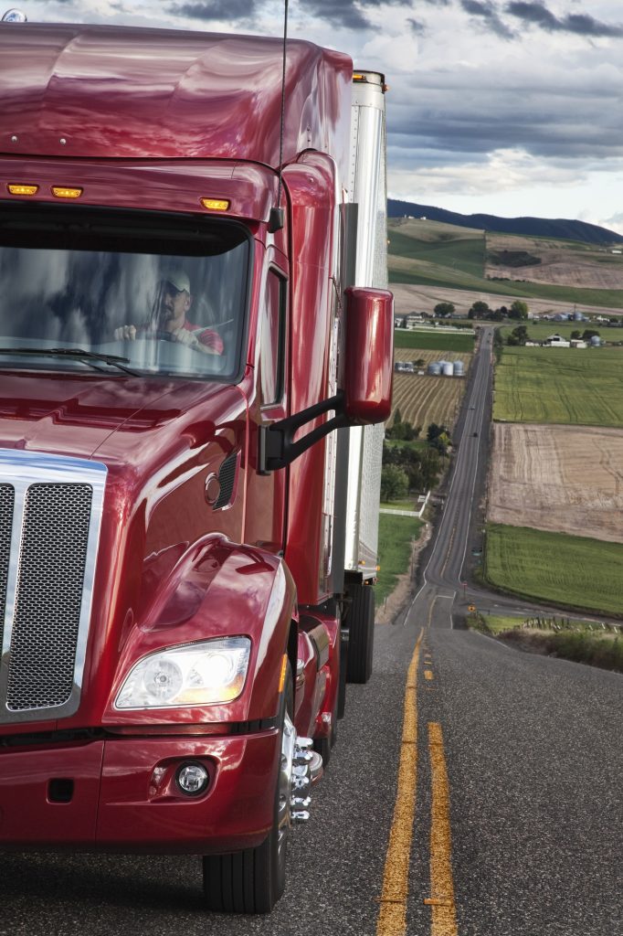 Close up view of the cab and driver of a commercial truck on the highway.